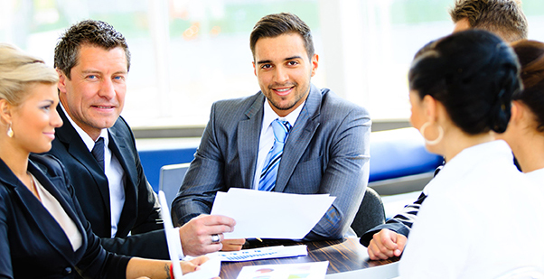 34313796 - portrait of young handsome businessman in office with colleagues in the background